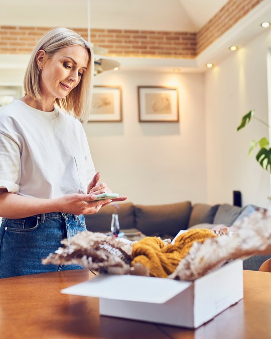 Lady with an opened parcel organising the return on her smartphone.