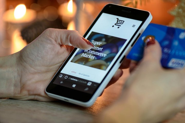 Close-up of a person shopping online on a smartphone using a credit card, representing the growth of mobile e-commerce and digital purchasing behavior.