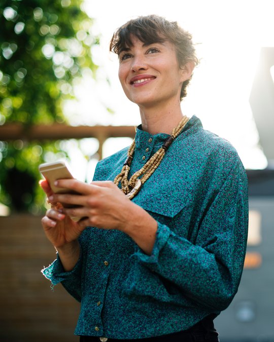Girl in green shirt looking at smartphone with shipping apps.