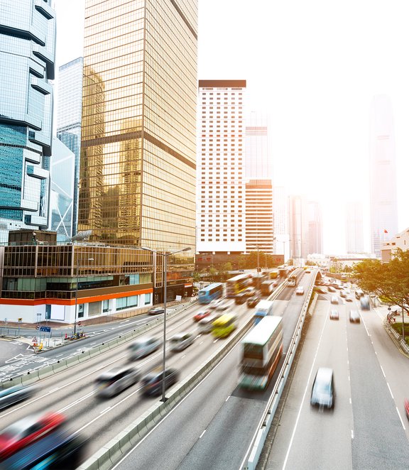 Busy urban highway with motion-blurred traffic surrounded by modern skyscrapers