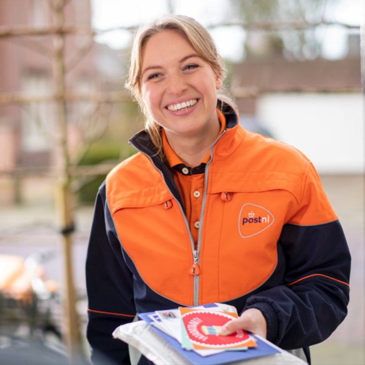 Smiling PostNL delivery worker holding mail and parcels