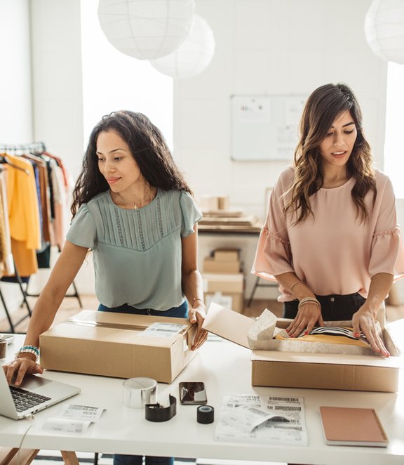 Women preparing clothing parcels at a table